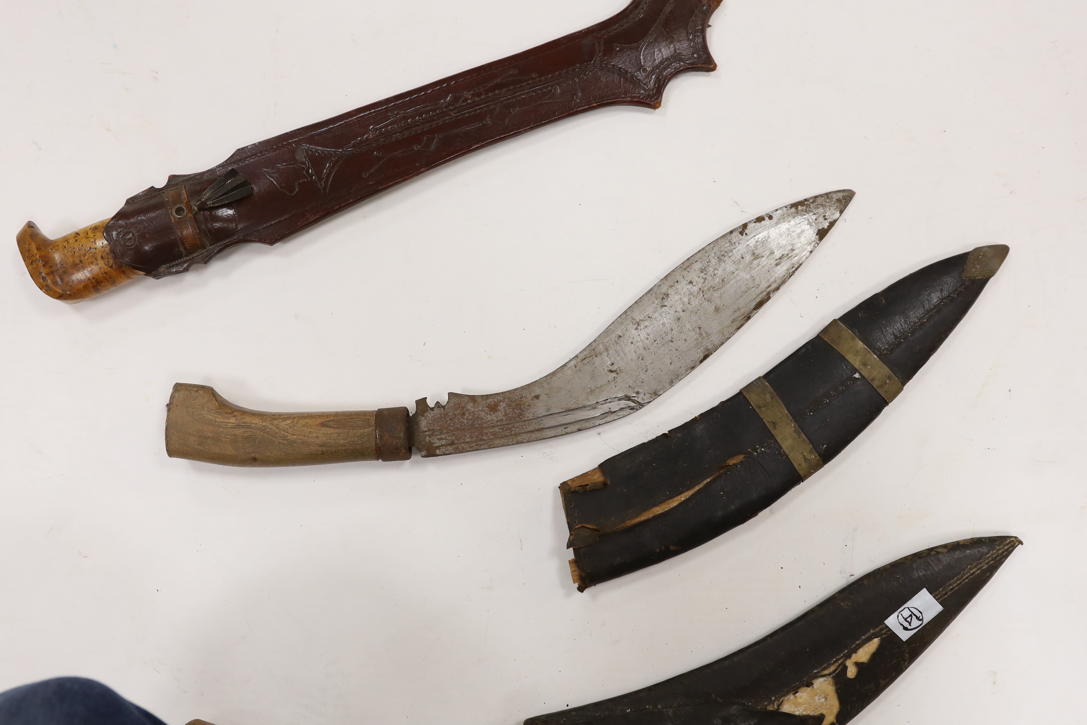 A large Finnish hunting knife, blade dated 1940 and burr wooden handle in its leather sheath, and two Indian kukri in their sheaths